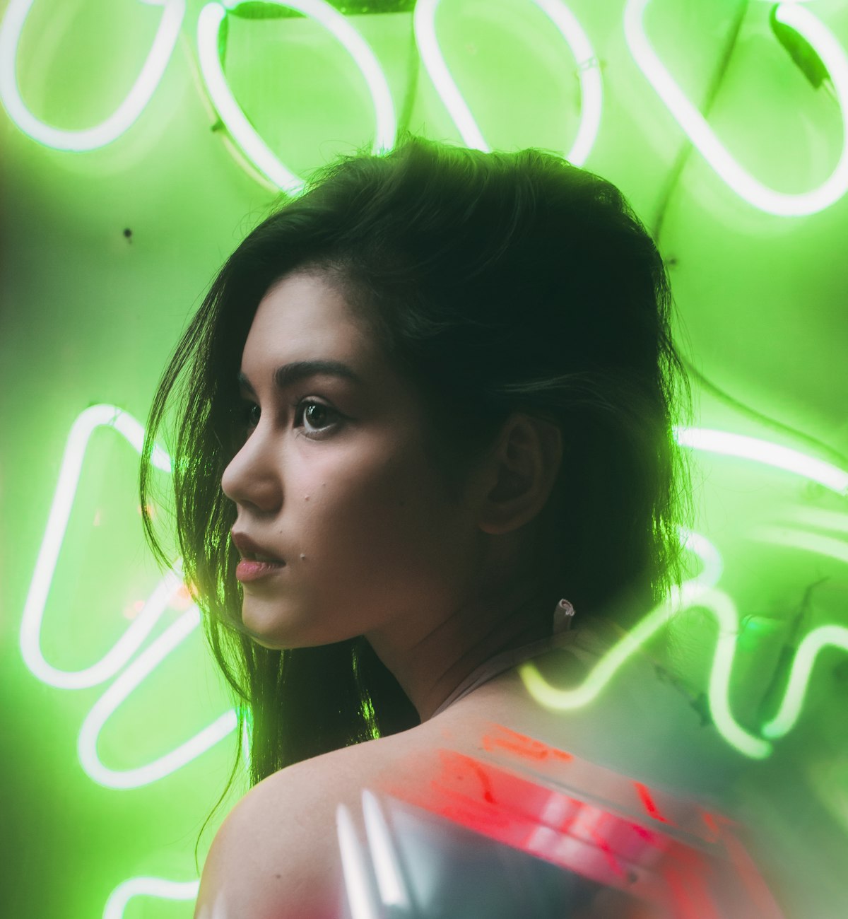 Woman in profile lit by bright green neon