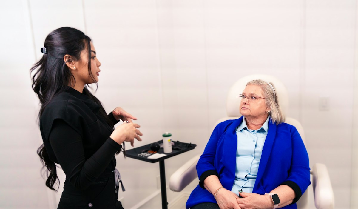 A clinician talking with a seated patient in a bright exam room