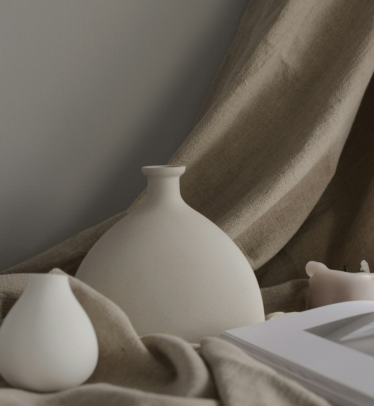 Two white ceramic vases against a soft shadowed wall